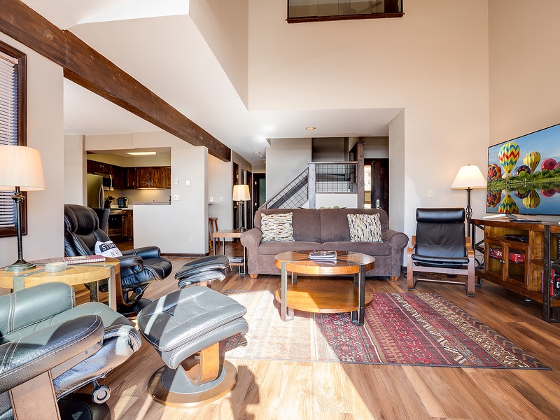 Unwind in your spacious living room where exposed beams meet modern comfort. Sink into plush seating, enjoy mountain views on the smart TV, and savor the warm hardwood floors beneath your feet.