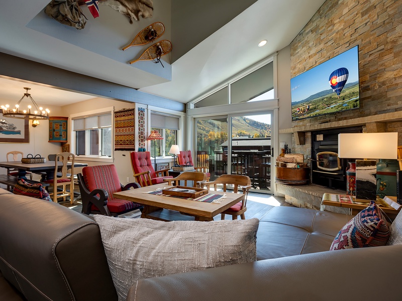 Settle into your cozy living space with mountain views through tall windows, a warm fireplace, and inviting seating where you can unwind and soak in the charm.