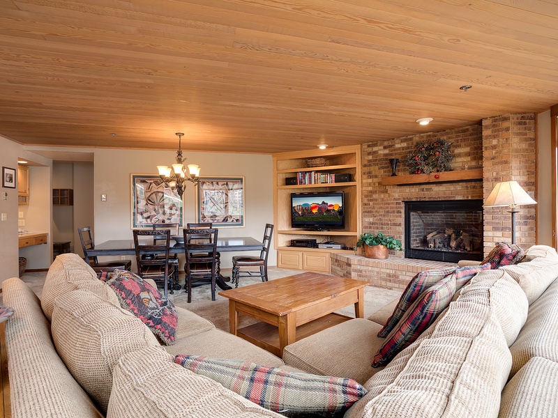 Picture yourself relaxing in this spacious living room with its warm wood ceilings, cozy fireplace, and comfy sofas—perfect for gathering with loved ones or unwinding after a day of adventure.