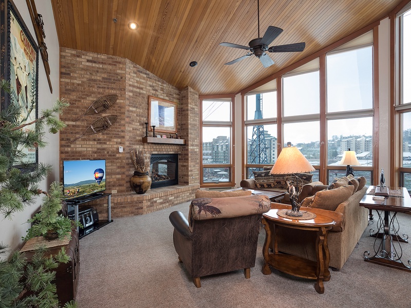 Curl up in your cozy living room with soaring wood ceilings, a warm fireplace, and panoramic windows framing stunning lakeside and mountain views—your perfect retreat awaits.