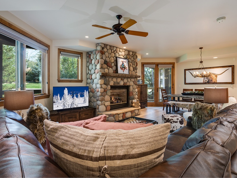 Sink into plush leather seating beside a warm river-rock fireplace. Your open-concept retreat features natural wood accents, high ceilings, and views of the outdoors—perfect for relaxing after a day of adventure.