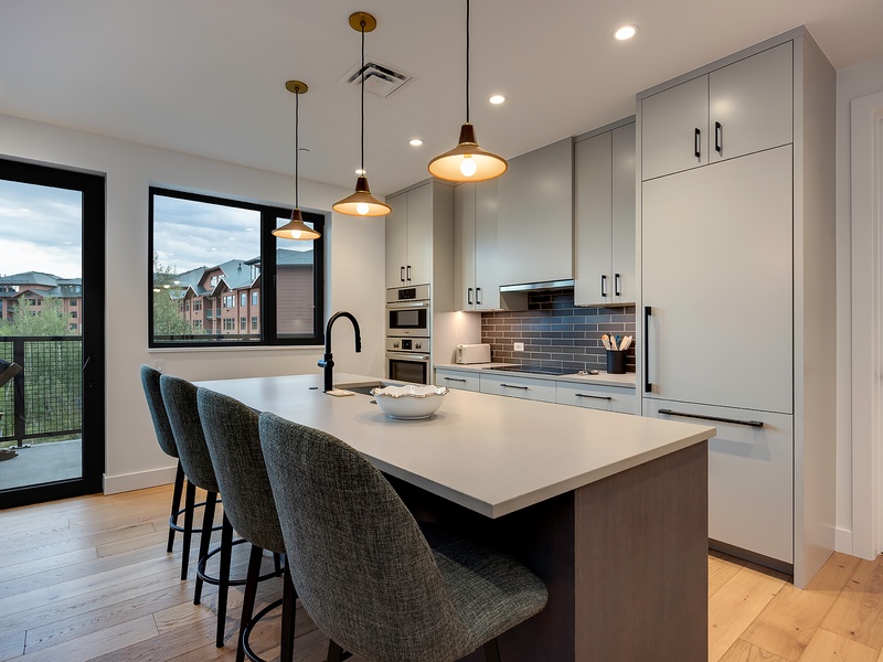 Your modern kitchen features sleek cabinetry, a spacious island with seating, and warm pendant lighting that creates an inviting space for cooking and gathering.