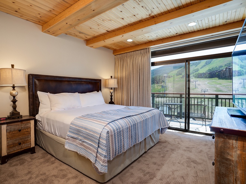 Wake up to mountain vistas framed by your private balcony. Sink into crisp linens under exposed beams, where modern comfort meets alpine charm in your cozy retreat.