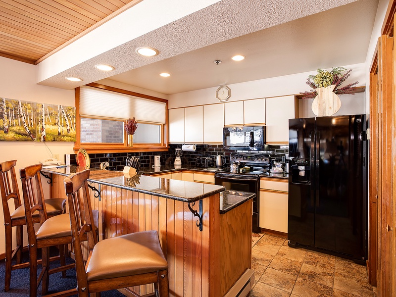 Your fully equipped kitchen invites home-cooked meals, featuring sleek granite countertops, modern black appliances, and a cozy breakfast bar perfect for morning coffee or evening conversations.