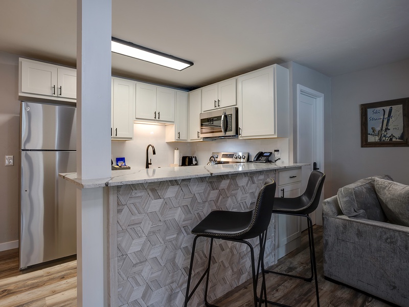 This stylish open-concept space features a fully equipped kitchen with modern appliances and a chic breakfast bar where you can enjoy your morning coffee.