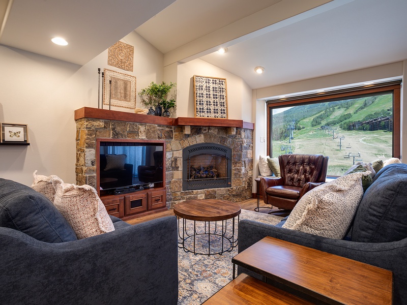 Unwind in your inviting living room, where plush sofas face a stone fireplace and mountain vistas—perfect for cozy evenings after a day of adventure.