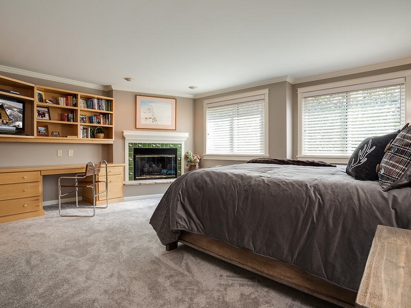 Picture yourself unwinding in this spacious bedroom with plush bedding, a cozy fireplace, and a dedicated workspace—your perfect retreat after mountain adventures.