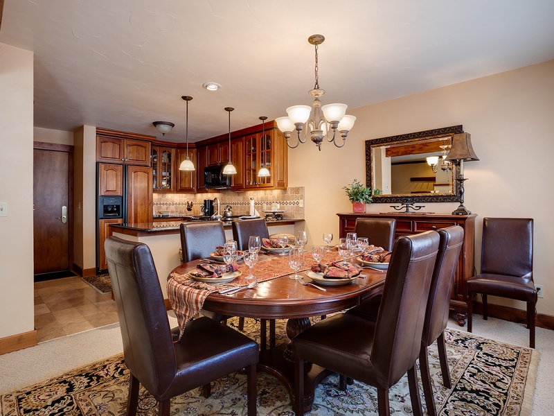 Gather around this elegant dining table, where your group can enjoy home-cooked meals together in comfort. Rich wood cabinetry and warm lighting create the perfect setting for memorable evenings.