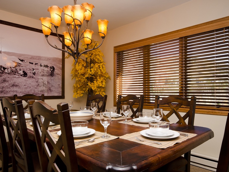 Gather around this handsome dining table with seating for eight, where memorable meals and laughter await beneath warm chandelier lighting and rustic touches.