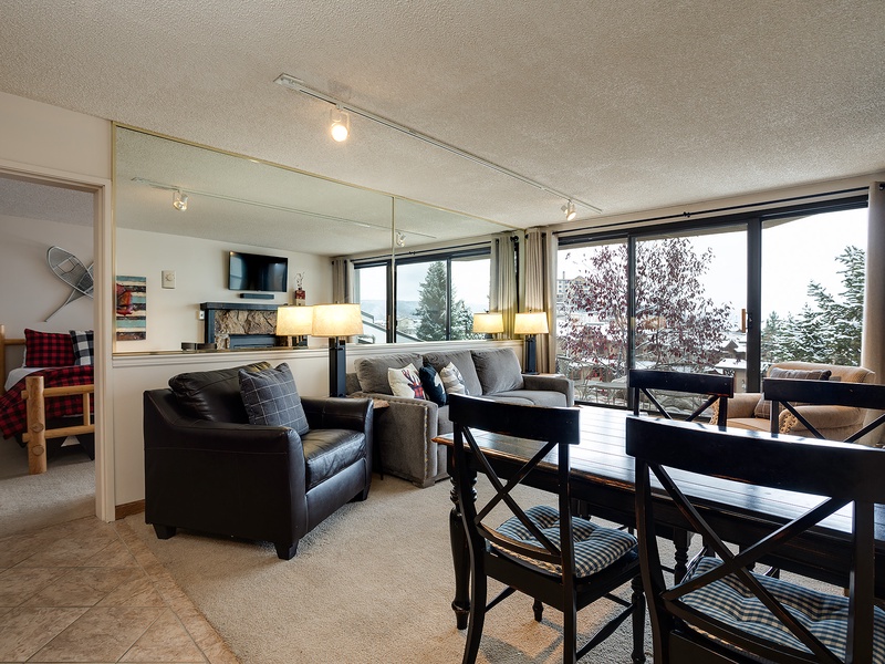 Relax in your open-concept living and dining area, where cozy seating, a warm fireplace, and stunning lake views through floor-to-ceiling windows create the perfect retreat for memorable evenings.