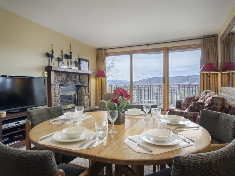 Relax in this welcoming living and dining space with a cozy fireplace, mountain views, and everything set for memorable meals during your stay.