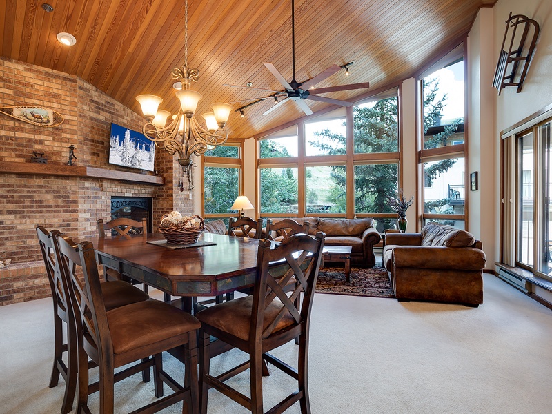 Gather around the warm brick fireplace or settle into plush leather seating while soaking in sweeping tree views through floor-to-ceiling windows. A perfect spot for meals, conversations, and unwinding together.