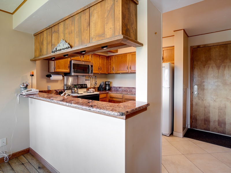 Your fully equipped kitchen features granite countertops, modern appliances, and warm wood cabinetry—everything you need to prepare meals during your mountain getaway.