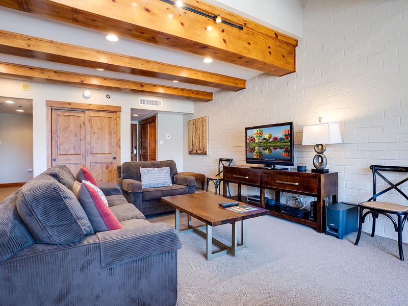 Unwind in your spacious living room with vaulted wood-beam ceilings, comfortable seating, and all the amenities you need for a relaxing stay.