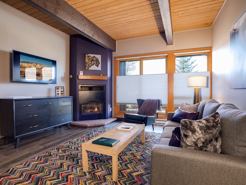 Sink into plush seating by your private fireplace, where warm wood tones and mountain light create your perfect retreat after a day of adventure.
