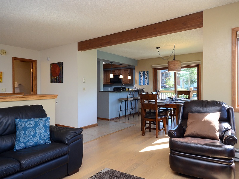 Settle into comfortable leather seating as sunlight streams through large windows, where your open-concept living, dining, and kitchen areas invite easy relaxation and memorable gatherings.