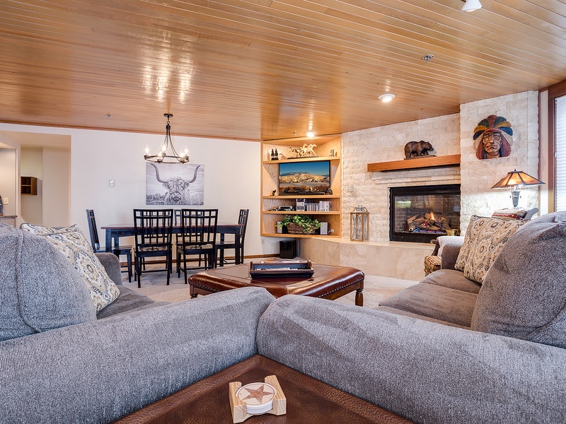 Unwind in your spacious open-concept living area with cozy sofas, a warm stone fireplace, and rustic Western decor that invites relaxation after a day exploring.