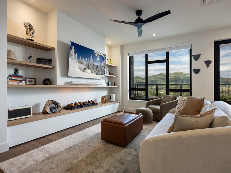 Sink into plush seating in this modern living room where panoramic mountain views through floor-to-ceiling windows create your perfect mountain retreat backdrop.