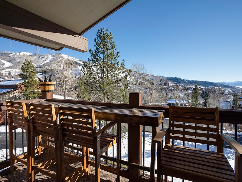 Expansive mountain views frame the covered terrace with outdoor seating, overlooking snow-dusted peaks and the valley below—perfect for morning coffee or evening relaxation.
