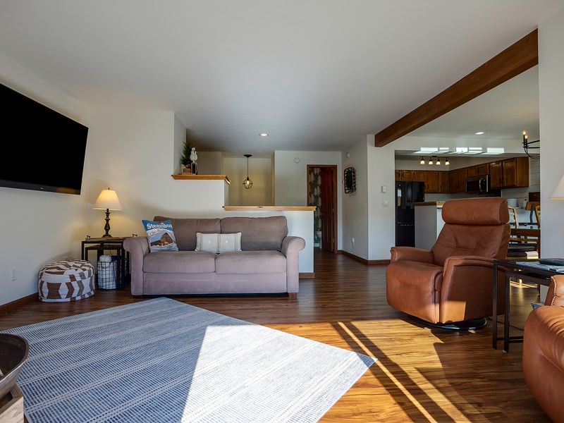Sunlight streams through your open-concept space, where warm wood tones and cozy leather seating invite you to unwind in total comfort.
