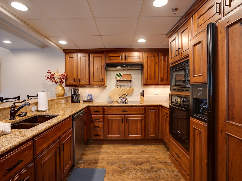 Step into your fully-equipped kitchen featuring rich wood cabinetry, granite countertops, and modern appliances—perfect for preparing family meals during your stay.