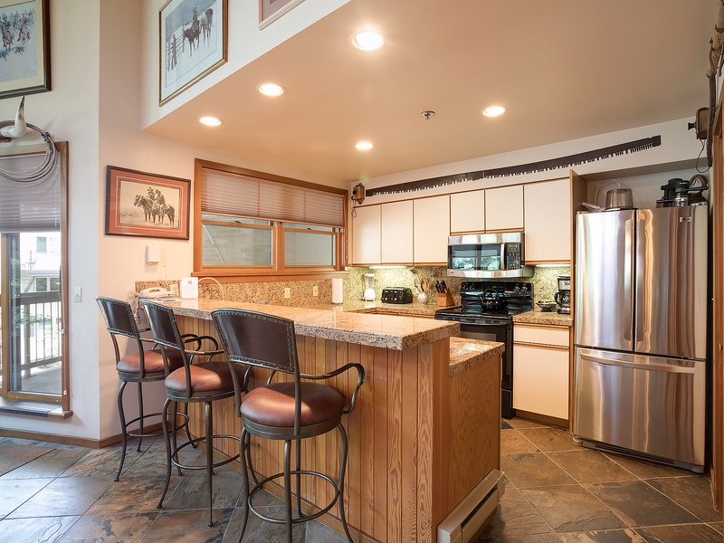 Your fully equipped kitchen awaits with granite counters, stainless appliances, and a cozy breakfast bar perfect for morning coffee or evening conversations with loved ones.