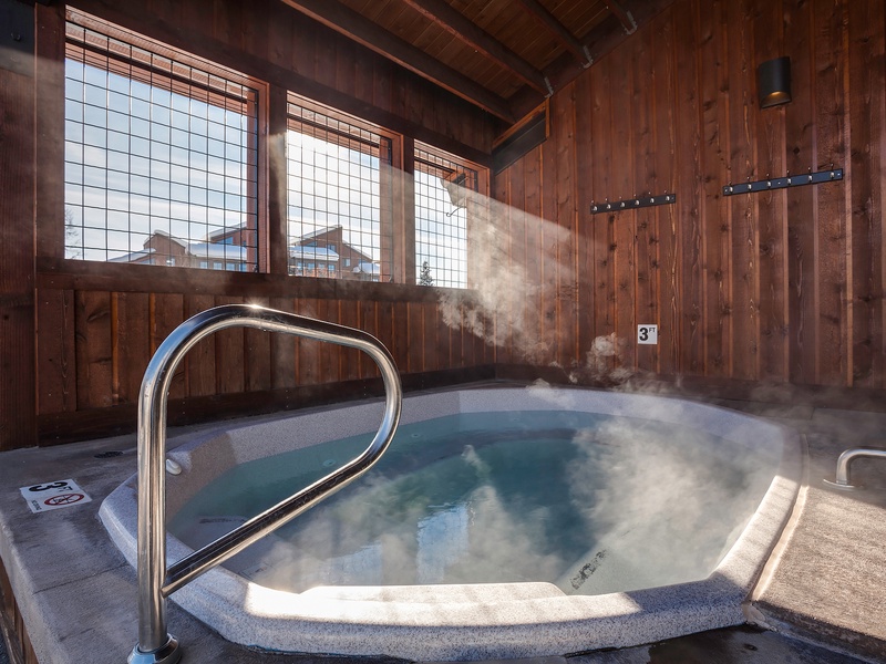 Sink into the steaming hot tub surrounded by warm wood and natural light filtering through traditional screens—your perfect mountain retreat awaits.