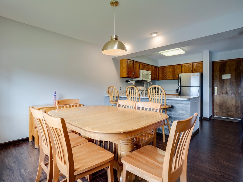 Step into your bright, open living area where a spacious dining table invites family meals and game nights. The full kitchen awaits your culinary adventures, complete with modern appliances and all the essentials.