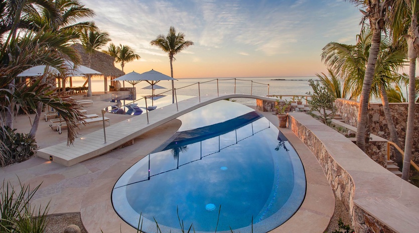 Beachfront infinity pool framed by swaying palms meets tropical ocean views—a stunning backdrop to unwind as the sun dips over the horizon.