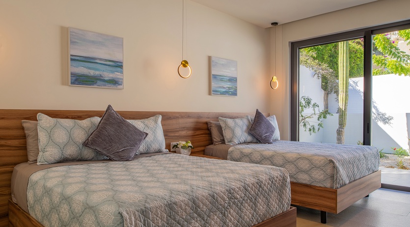 Unwind in your elegant twin bedroom with modern coastal touches, where warm wood tones and soothing ocean artwork create a peaceful retreat.