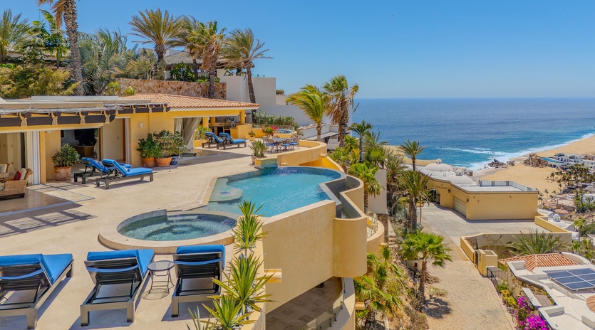 Stunning beachfront villa with infinity pool, hot tub, and panoramic ocean views surrounded by swaying palms.