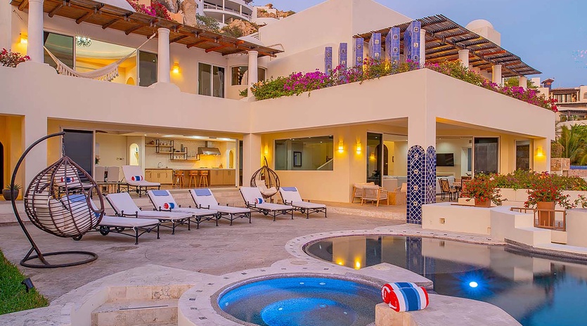 This hillside villa offers a private pool, hot tub, and multiple outdoor lounging areas. Vibrant bougainvillea cascades over terraces, while the open-air design invites you to relax poolside or retreat to shaded seating under the pergola.