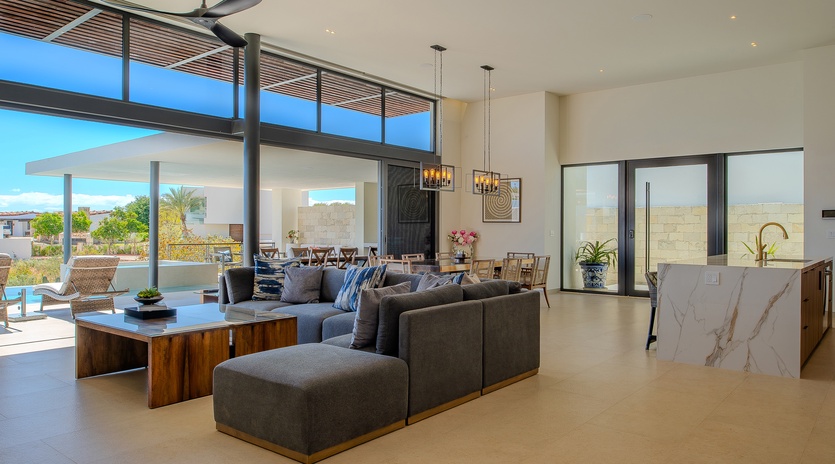 Sink into the plush sectional sofa where floor-to-ceiling windows flood your space with natural light and stunning views.