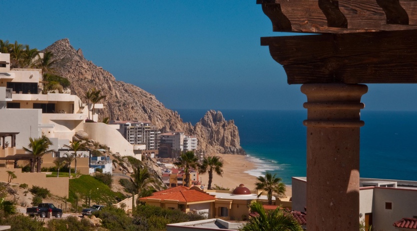 This coastal property offers stunning views of dramatic rock formations meeting turquoise waters, with golden sand beaches stretching along the horizon in a picturesque seaside setting.