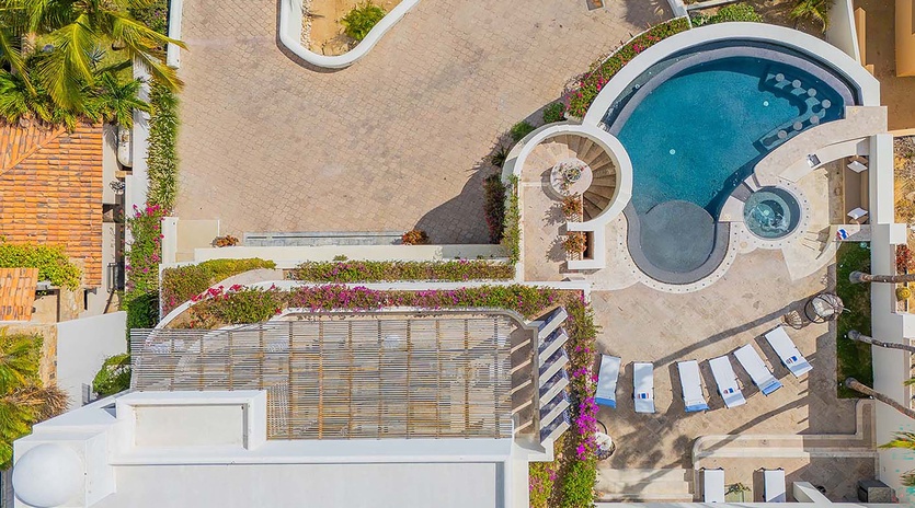 The property features a sparkling pool surrounded by lush tropical gardens, poolside lounge chairs, and an integrated hot tub, creating an inviting outdoor oasis for relaxation.