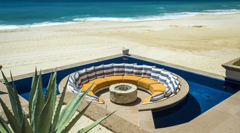 Stunning beachfront property featuring a circular fire pit seating area with direct ocean access and pristine sandy beach.