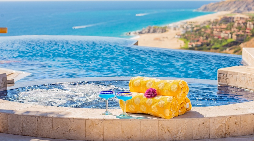 Sink into luxury at your infinity pool where yellow towels and cocktails await your perfect seaside escape.