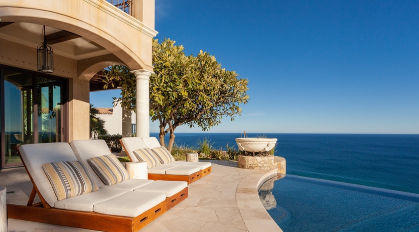 Lounge chairs by poolside with ocean views