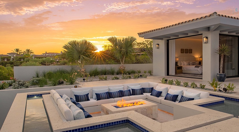 Stunning desert property surrounded by palm trees and native landscaping, offering a tranquil retreat with desert views as the sun sets over the horizon.
