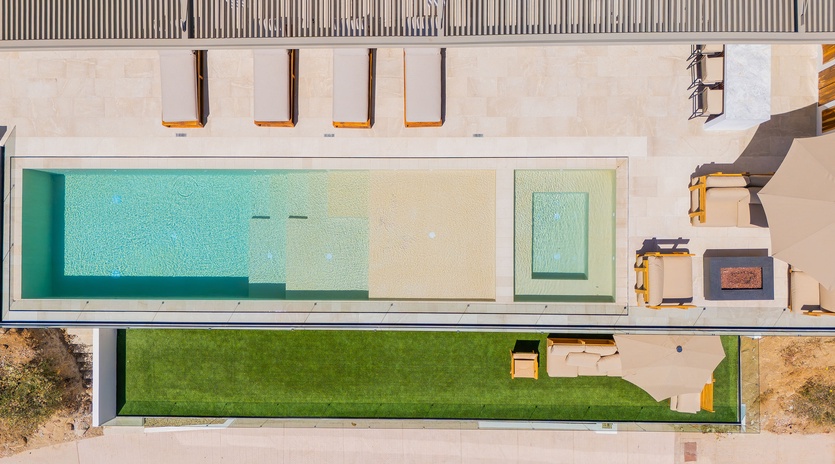 Modern architectural property featuring a stunning swimming pool, manicured lawn, and contemporary design elements captured from above.