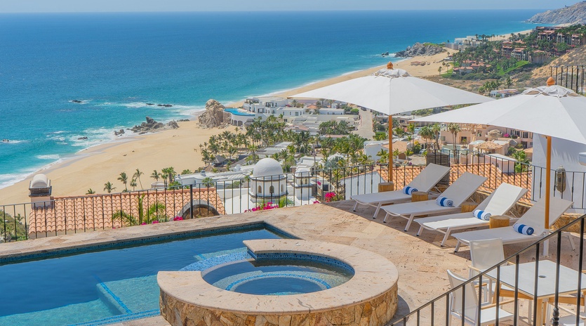 Stunning oceanfront terrace with infinity pool and hot tub overlooking pristine beach and turquoise waters.