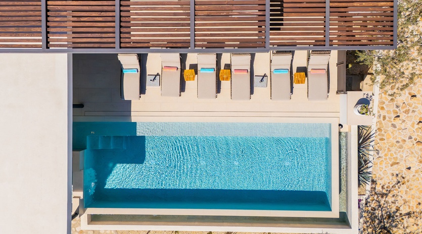 Aerial view of the property's swimming pool area with modern poolside loungers and wooden privacy screening.