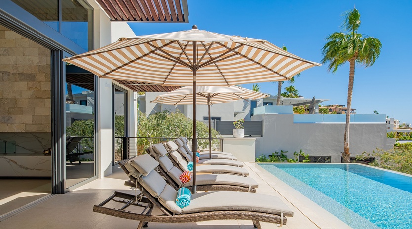Bask in your private poolside paradise with plush loungers and tropical shade umbrellas under endless blue skies.