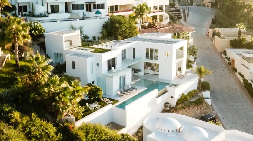 Modern white villa with private pool nestled among tropical palms in an exclusive residential area.