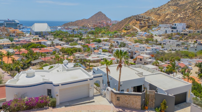 Aerial view of property nestled in a hillside coastal community with mountain and ocean views, palm trees, and proximity to local amenities.