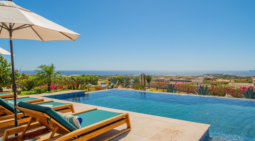 Infinity pool with ocean views and luxurious loungers surrounded by tropical landscaping.