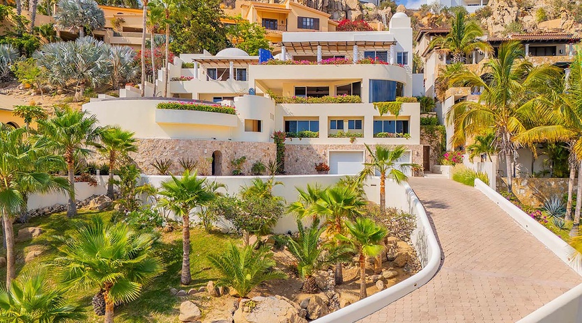 A striking hillside property nestled among tropical palms and native landscaping, offering sweeping views of the surrounding coastal community.