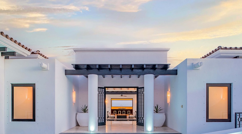 Modern Spanish-style architecture welcomes guests with elegant lighting and a dramatic sunset backdrop, setting the stage for your arrival experience.