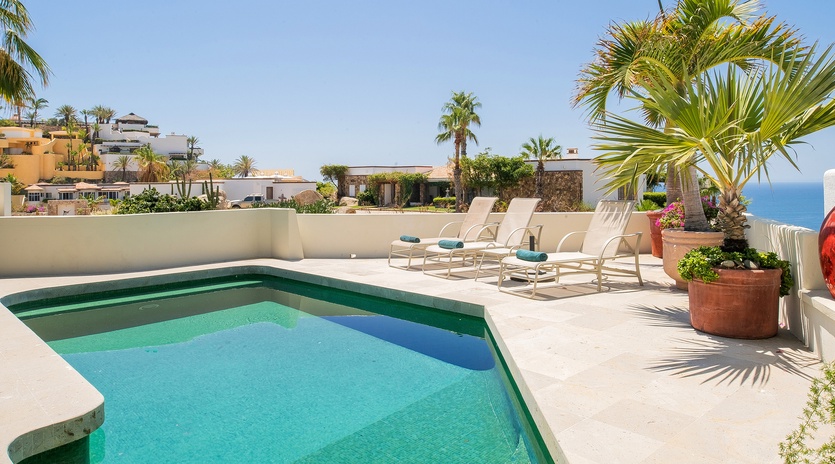 Poolside view with lounge chairs and ocean view