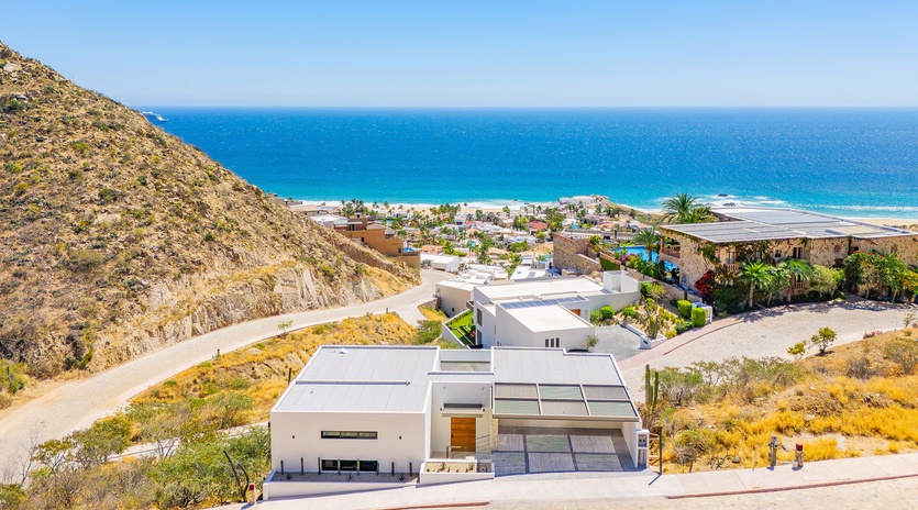 Modern hillside property overlooking pristine beach and turquoise waters in an exclusive coastal community.